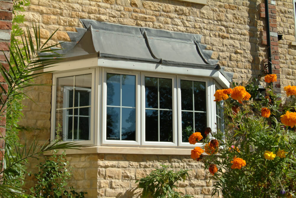 Logik chamfered white bay window on stone house